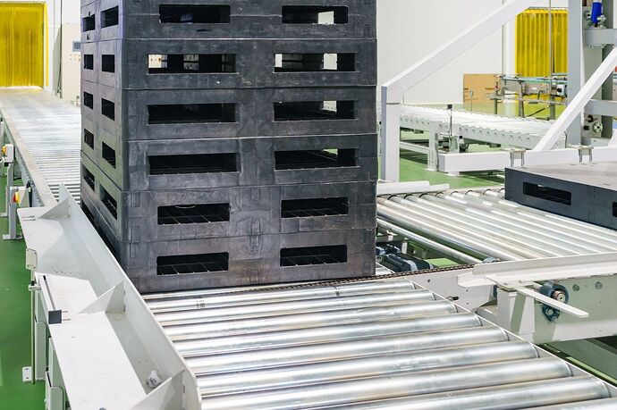 Plastic pallets stacked on a conveyor.