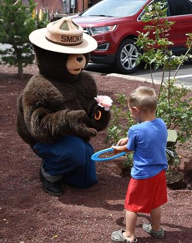 A young boy plays frisbee with Smokey Bear at his tree planting ceremony.