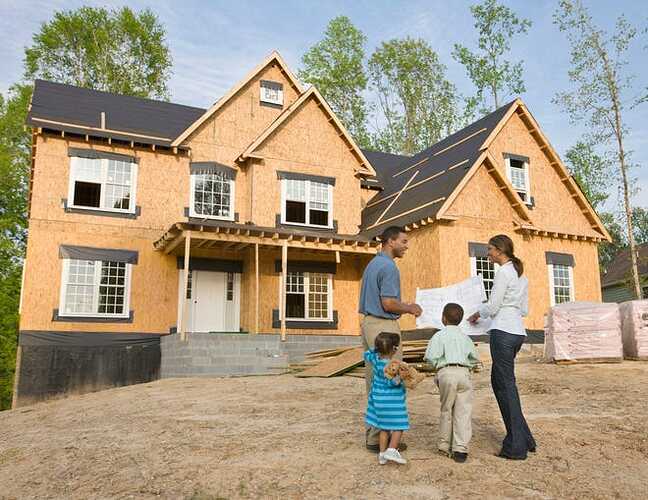 A family stands in front of a new house under construction.