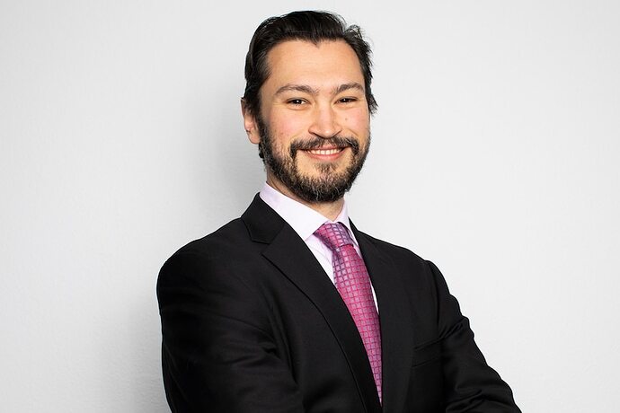 A man wearing a suit and tie smiling at the camera.