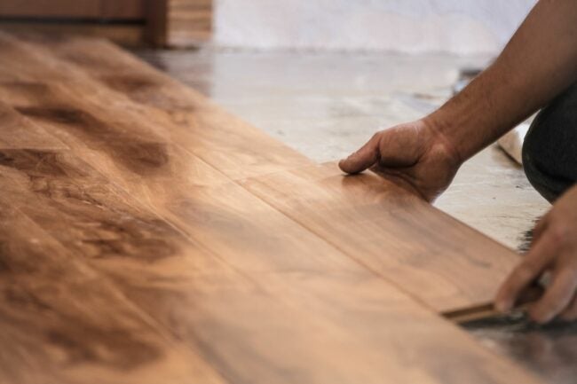 A close up of a person laying down wooden floor planks.