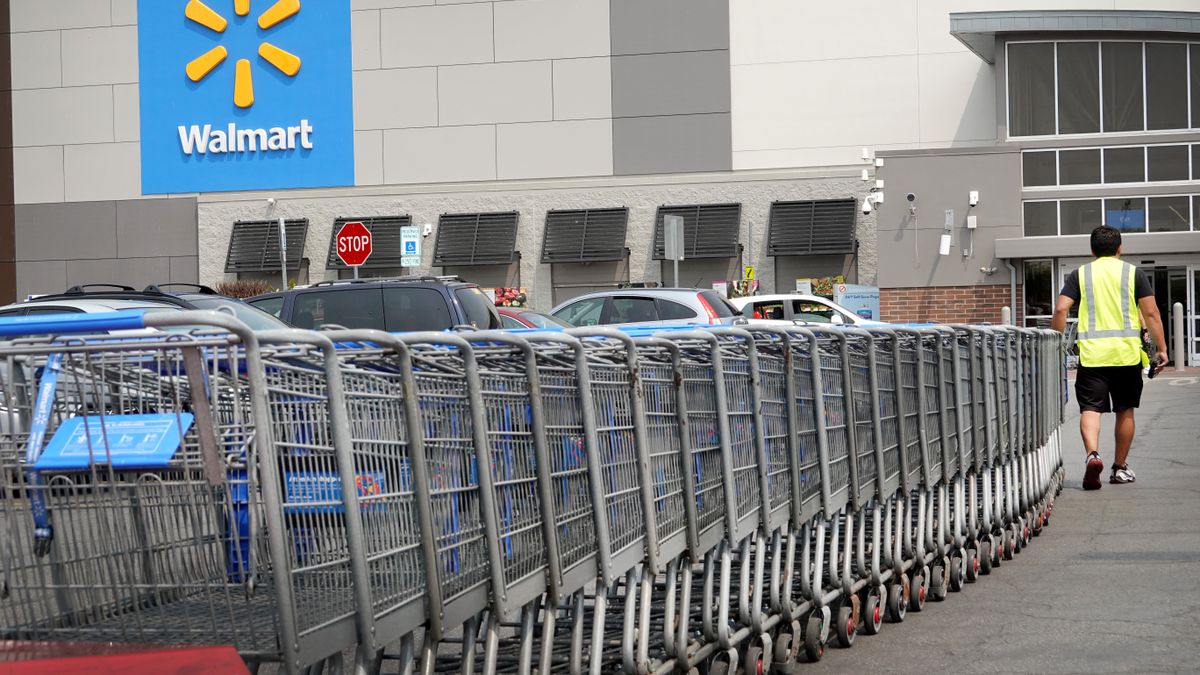 A worker collects shopping carts from the parking lot of a Walmart store on May 18, 2023 in Chicago, Illinois.